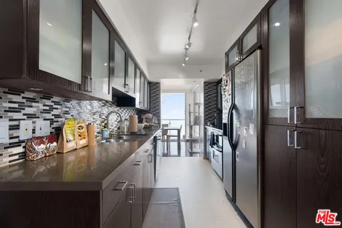 a kitchen with stainless steel appliances granite countertop a refrigerator a stove and a sink