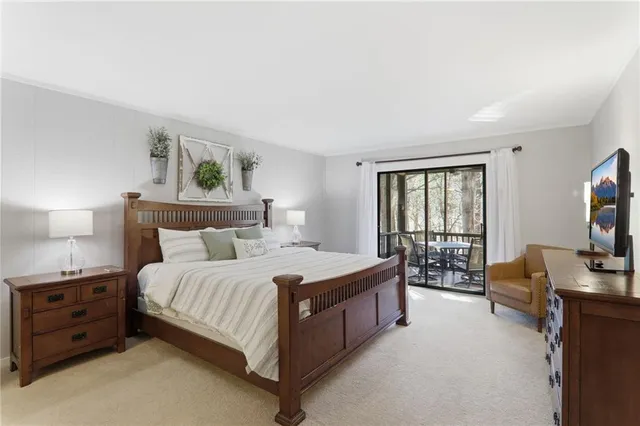 a bedroom with a bed a couch and a flat tv screen on the dresser