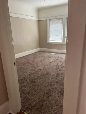 an empty room with wooden floor and a ceiling fan