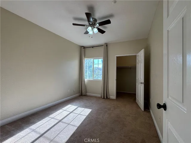 an empty room with wooden floor and a ceiling fan