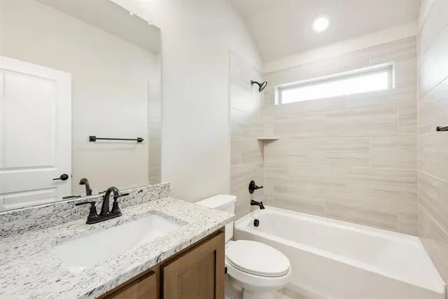 a bathroom with a granite countertop sink a toilet and bathtub