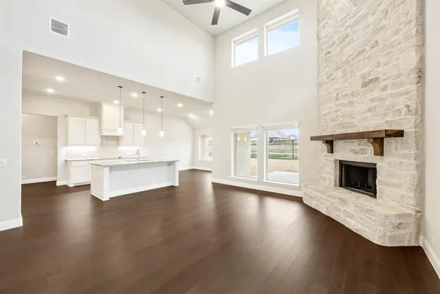 a view of an empty room with wooden floor and a kitchen