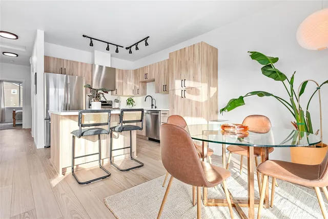 a view of a dining room with furniture one side kitchen view and wooden floor