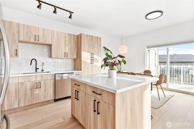 a kitchen with white cabinets a sink dishwasher and a stove with wooden floor