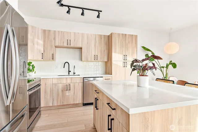 a kitchen with stainless steel appliances granite countertop a sink a stove and a refrigerator