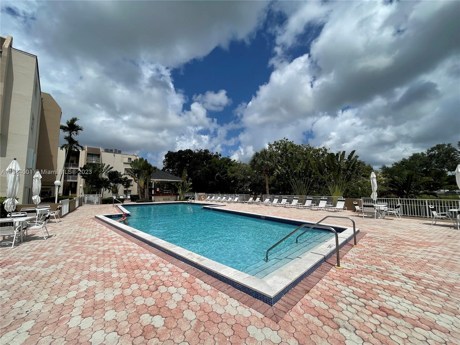 7765 Southwest 86th Street, Unit F2412 Miami, FL 33143 - Photo 6 of 53 a view of a swimming pool with a bench and lawn chairs