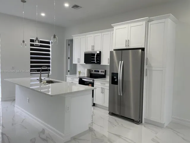 a kitchen with stainless steel appliances a refrigerator sink and microwave