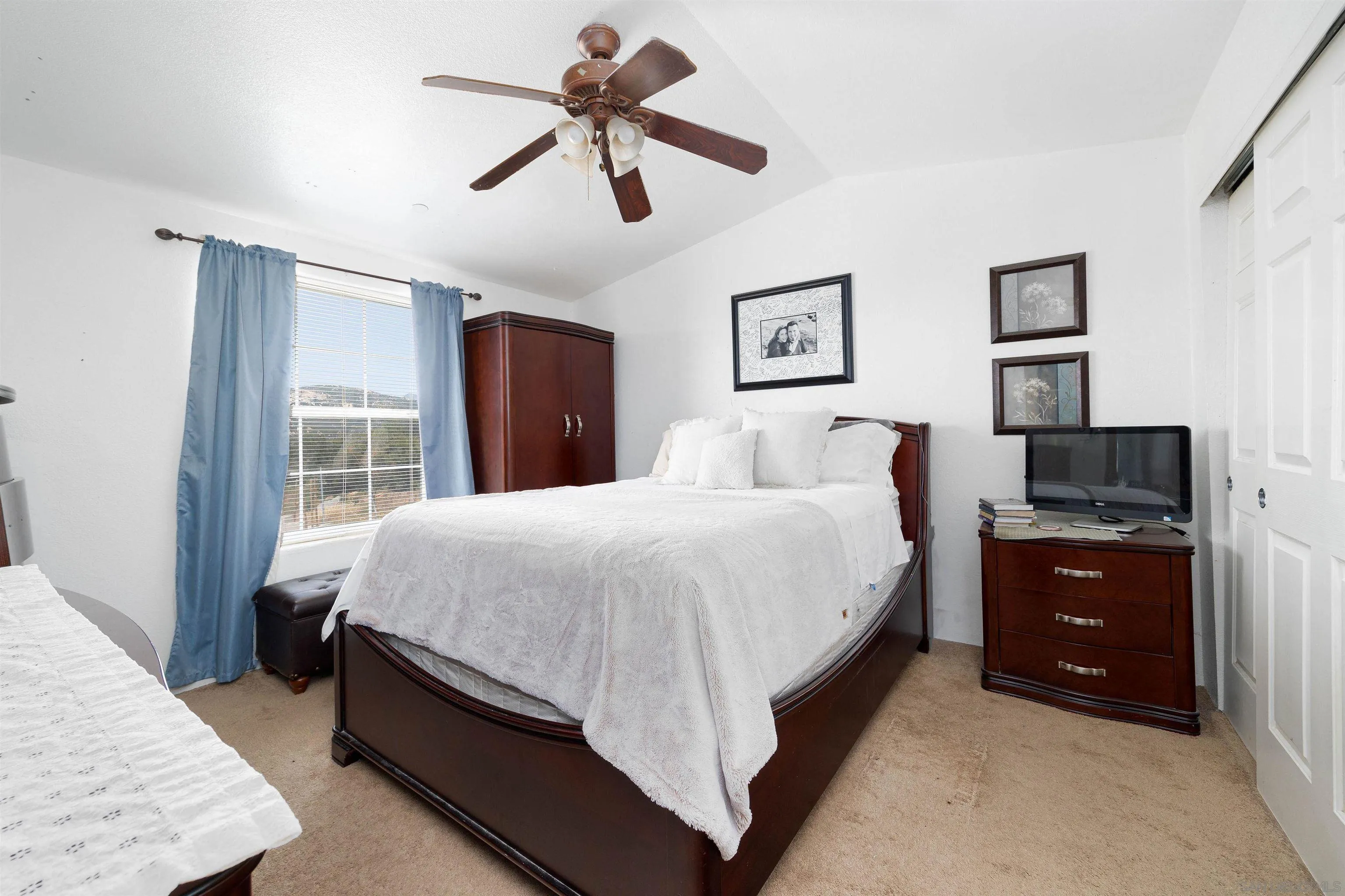 23744 Old Ranch Road Alpine, CA 91901 - Photo 11 of 17 a spacious bedroom with a bed a dresser and a chandelier