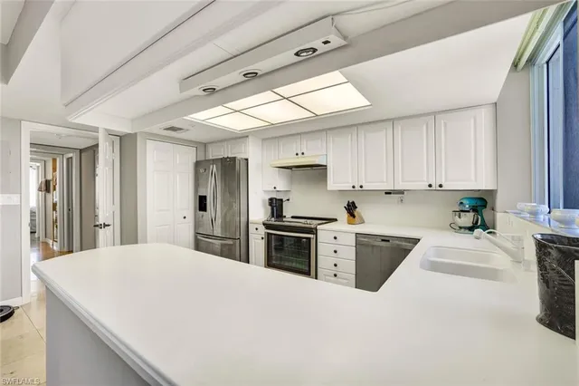 a kitchen with a stove a sink a refrigerator a window and cabinets