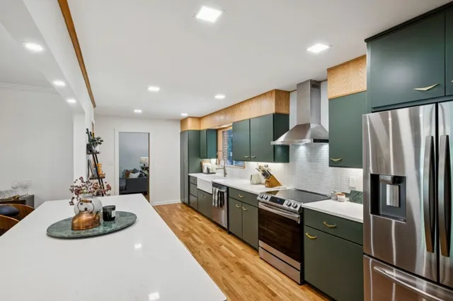 a kitchen with stainless steel appliances kitchen island granite countertop a sink and refrigerator