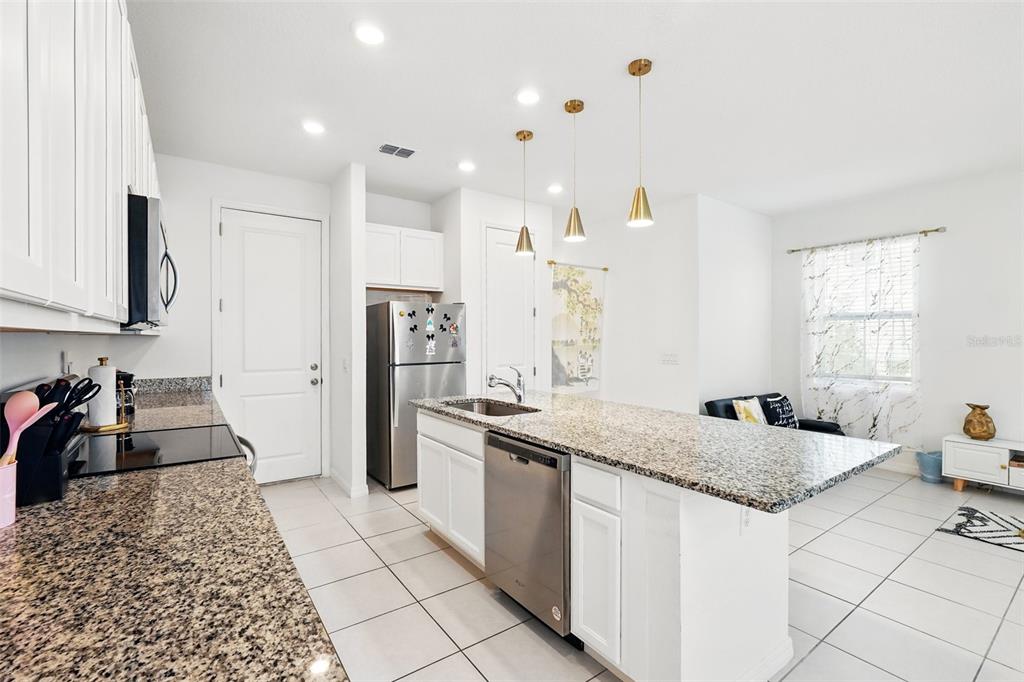 1421 Discovery Street Davenport, FL 33896 - Photo 13 of 44 a kitchen with stainless steel appliances granite countertop a sink stove and refrigerator