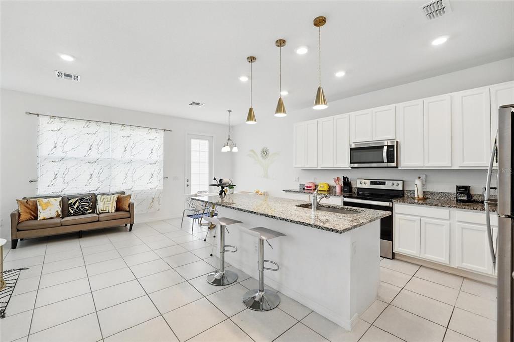 1421 Discovery Street Davenport, FL 33896 - Photo 7 of 44 a kitchen with stainless steel appliances kitchen island granite countertop a sink and cabinets