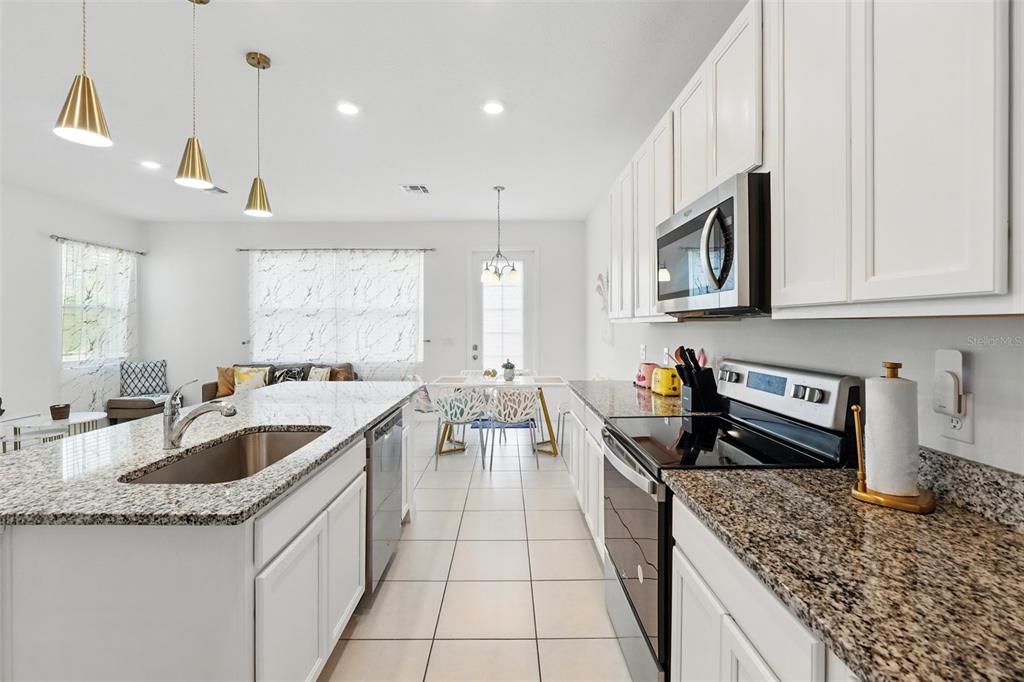 1421 Discovery Street Davenport, FL 33896 - Photo 9 of 44 a kitchen with stainless steel appliances granite countertop a sink stove and cabinets