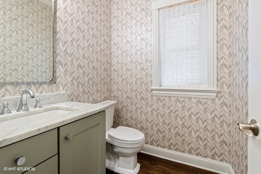 1248 West Grace Street, Unit 1 Chicago, IL 60613 - Photo 18 of 35 a bathroom with a granite countertop toilet a sink a mirror and a shower