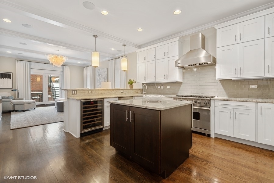 1248 West Grace Street, Unit 1 Chicago, IL 60613 - Photo 10 of 35 a kitchen with kitchen island granite countertop a stove top oven a chimney cabinets and wooden floor