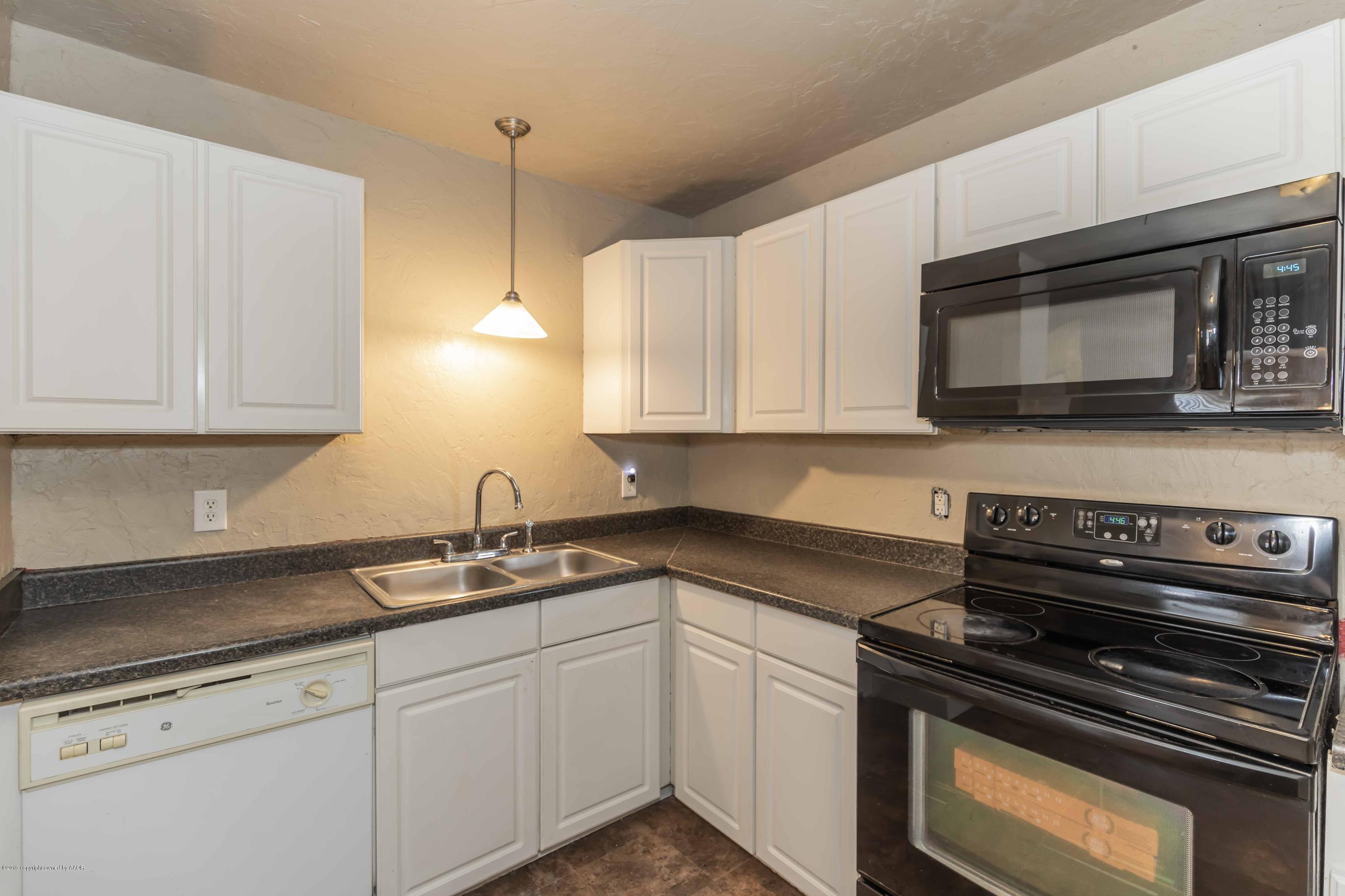1603 Southwest 48th Avenue Amarillo, TX 79110 - Photo 5 of 31 a kitchen with stainless steel appliances granite countertop white cabinets and a stove top oven