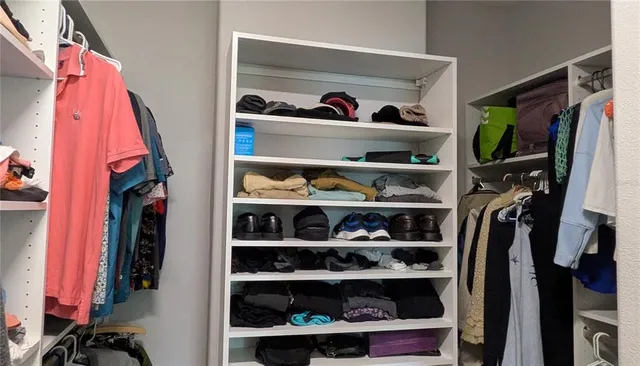 a view of walk in closet with clothes and shoes