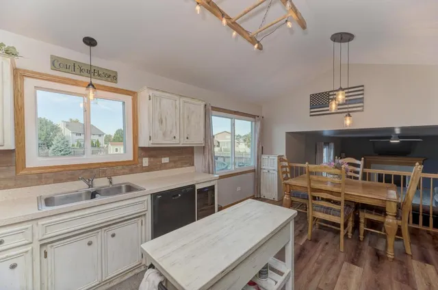 a kitchen with a stove a sink dishwasher a dining table and chairs with wooden floor