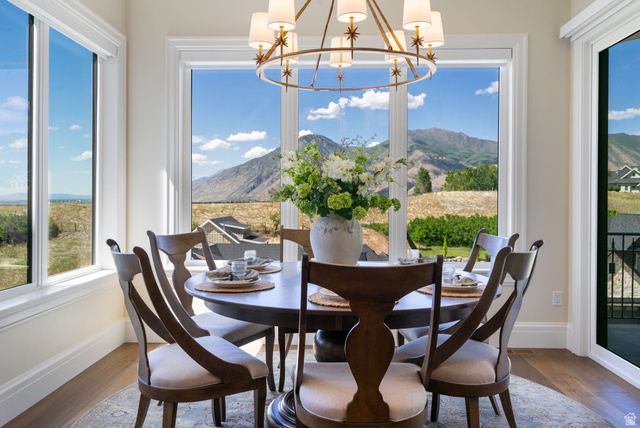 115 East Hidden Ridge Lane, Unit 42 Mapleton, UT 84664 - Photo 8 of 103 Dining area featuring extensive fenestration with mountain and distant field scenery, wood-finish flooring, a decorative round chandelier, and white baseboards