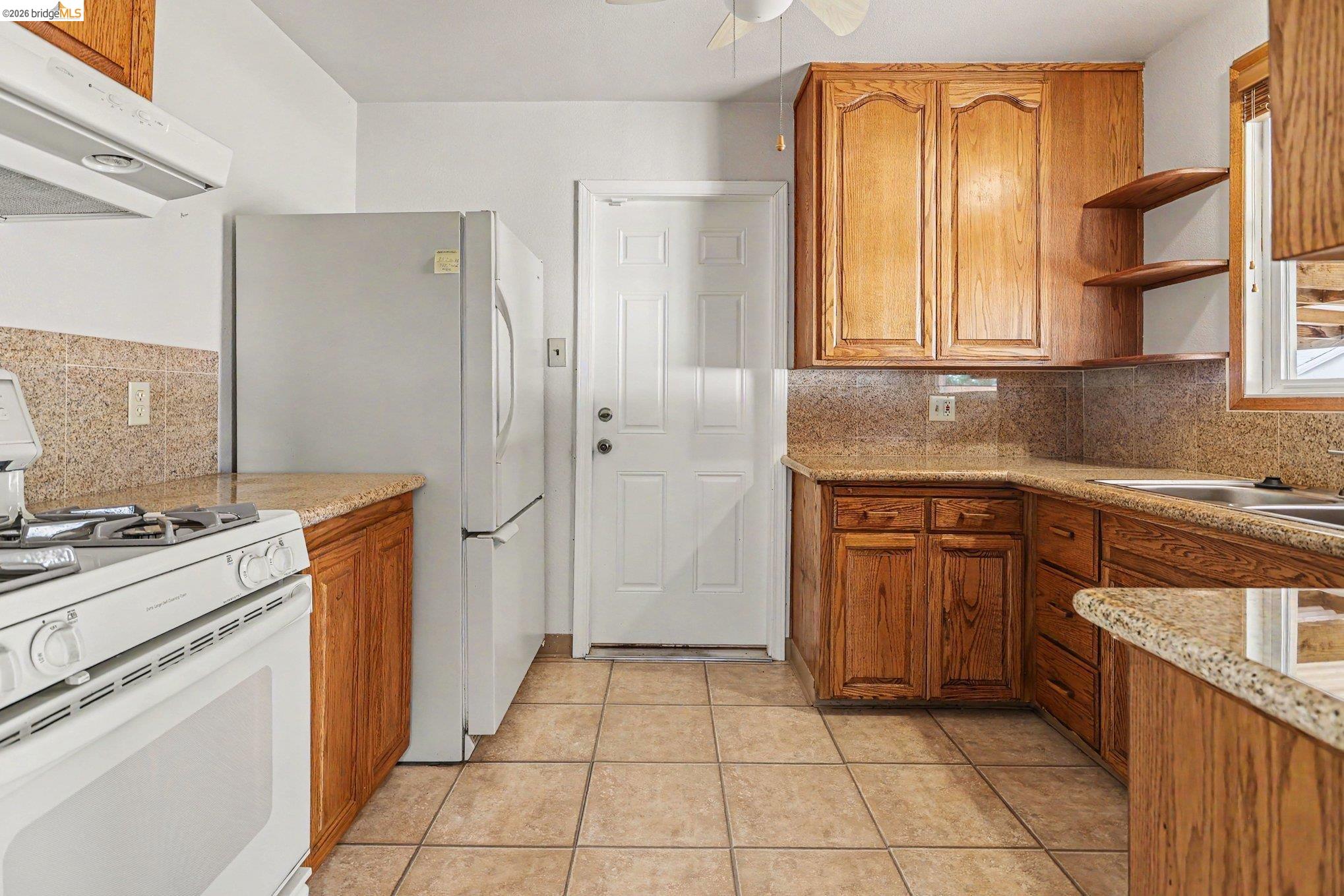 249 Madison Avenue Bay Point, CA 94565 - Photo 9 of 18 Kitchen featuring wood cabinetry, granite-look countertops, a tile backsplash, and tile flooring
