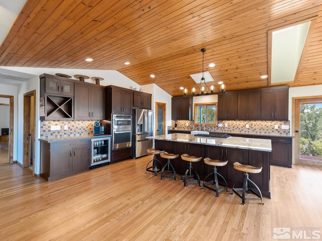 700 Saddleback Road Reno, NV 89521 - Photo 8 of 38 a kitchen with stainless steel appliances kitchen island granite countertop a table chairs and a refrigerator