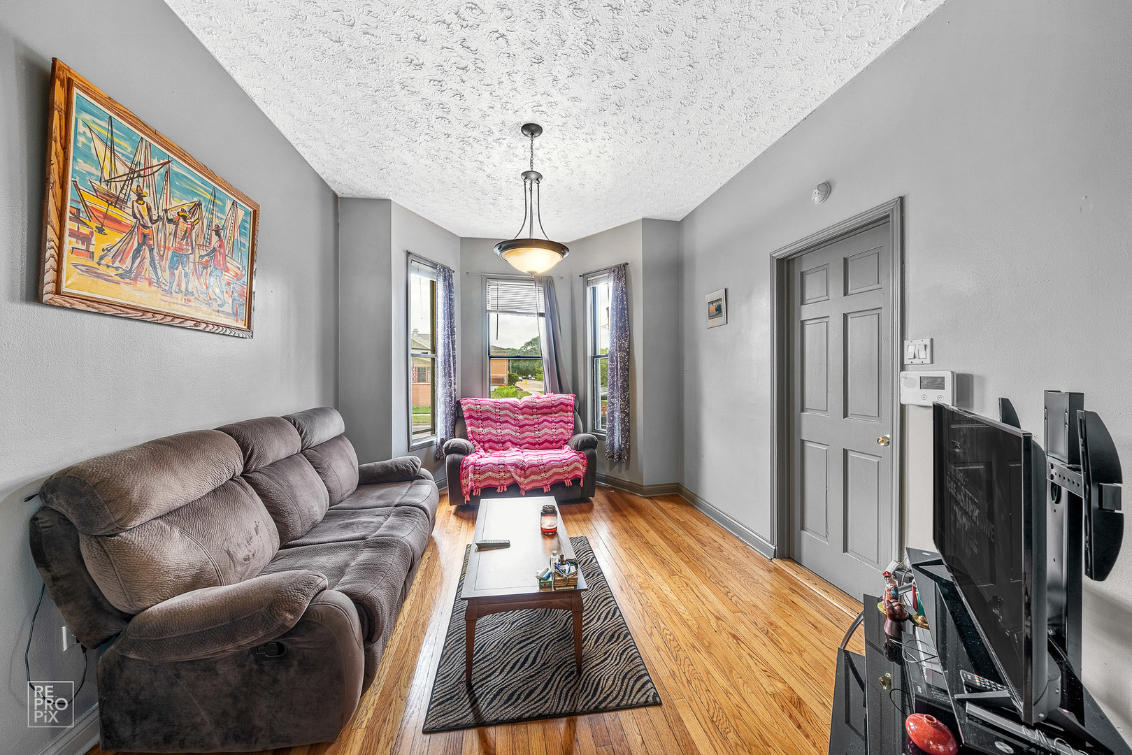 3101 Grove Avenue Berwyn, IL 60402 - Photo 2 of 14 a living room with furniture a flat screen tv and a chandelier