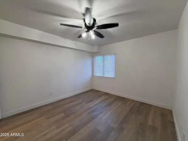 an empty room with wooden floor fan and windows