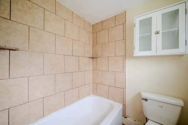 a bath tub sitting next to a white toilet and a shower
