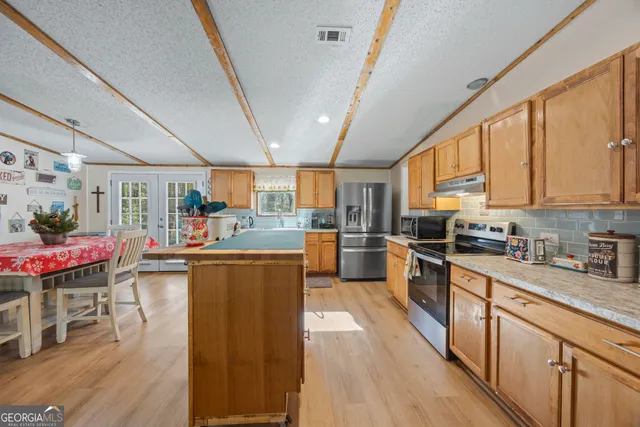 a kitchen with stainless steel appliances kitchen island granite countertop wooden floors and a view of living room