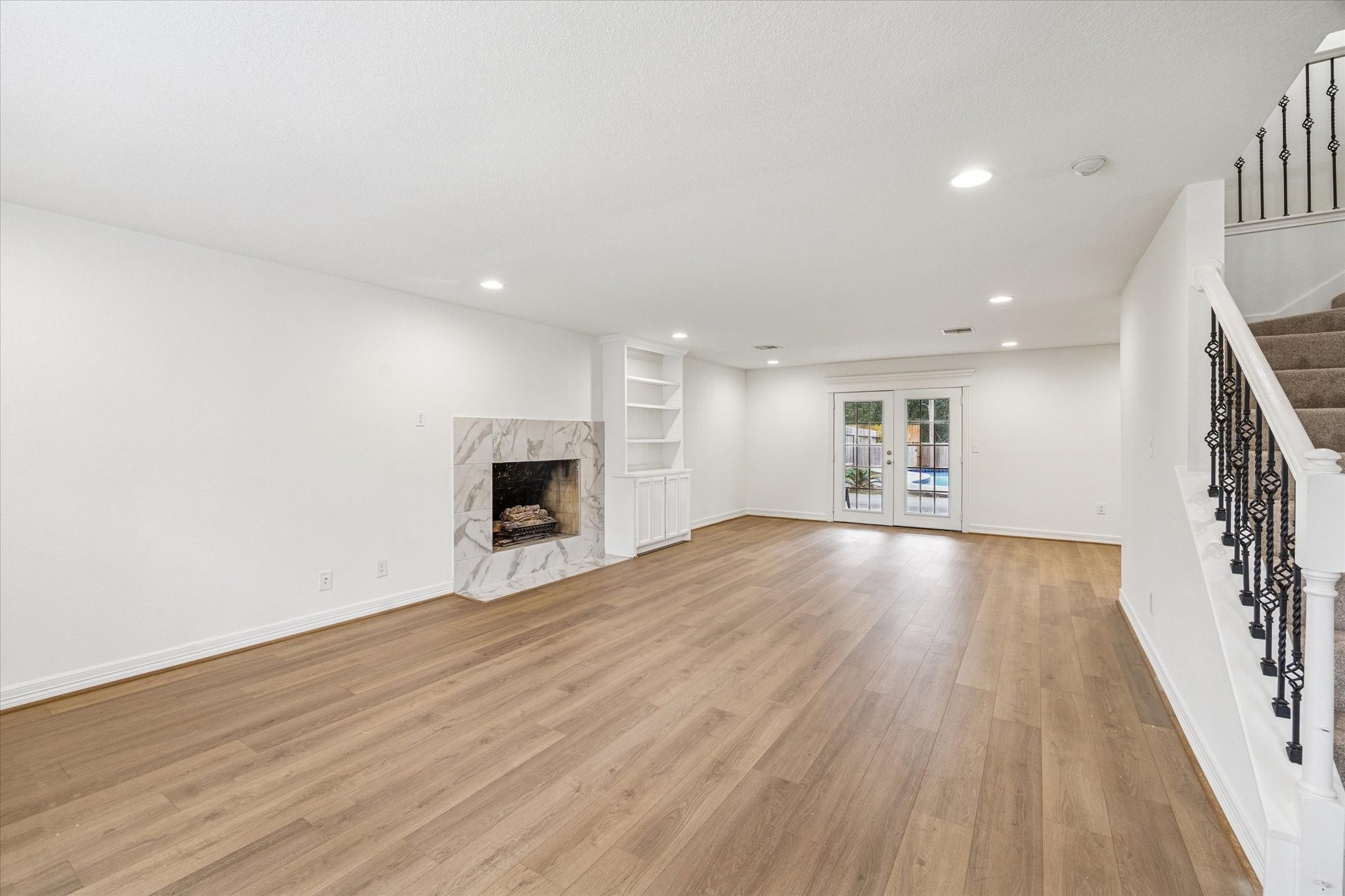 4314 Oxhill Road Spring, TX 77388 - Photo 3 of 22 Large open den with tile surround fireplace, built-in, engineered wood floors with French doors to covered patio and pool.