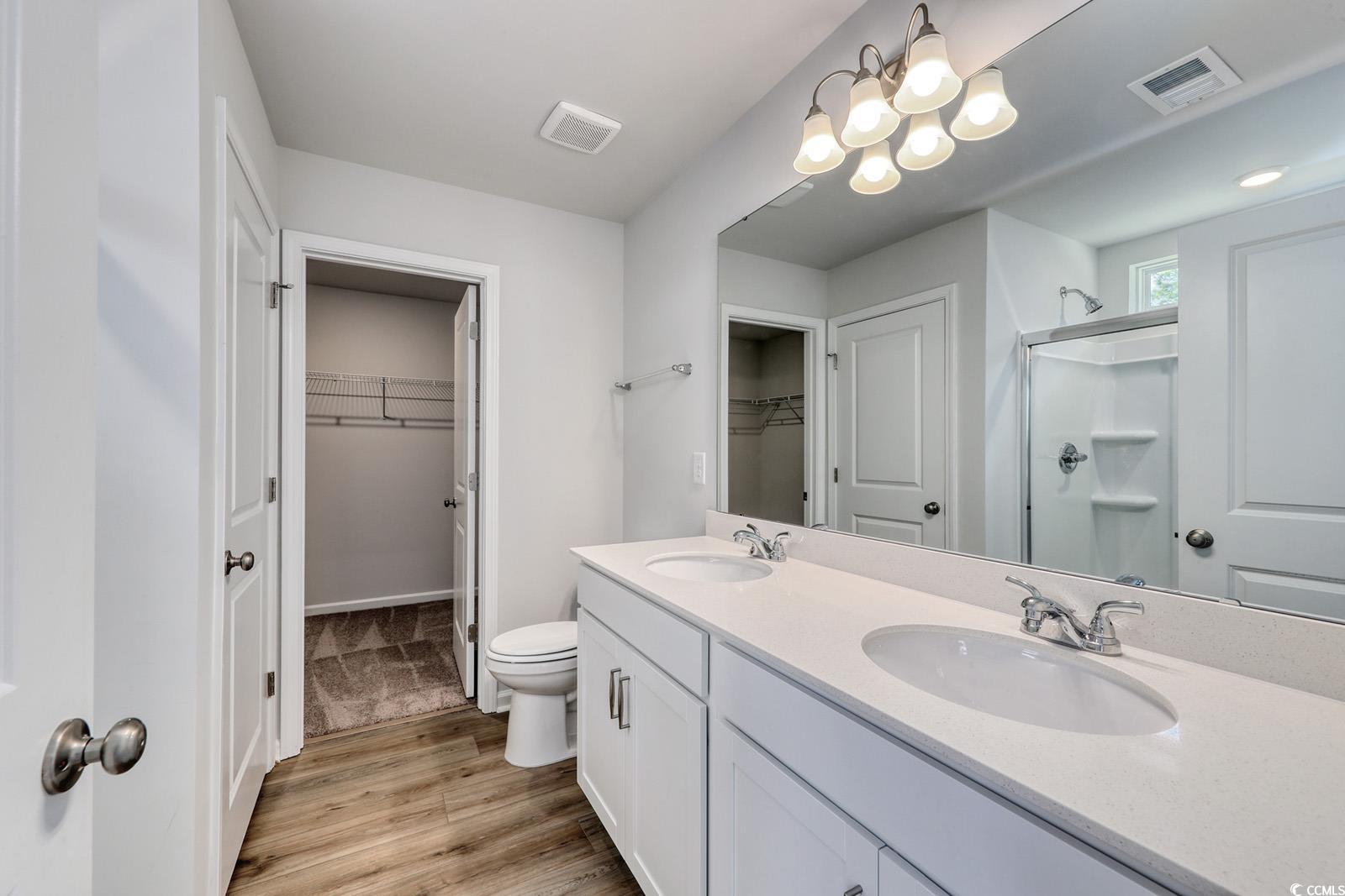 3416 Logan Street Conway, SC 29526 - Photo 16 of 30 Bathroom featuring a spacious closet, a shower stall, double vanity, and light wood-style floors