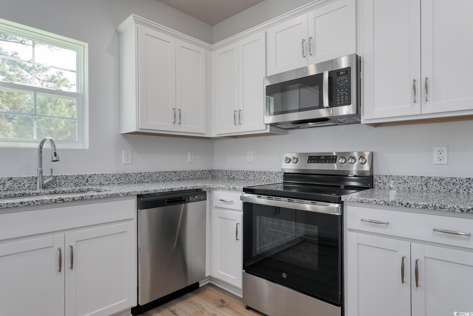 3416 Logan Street Conway, SC 29526 - Photo 6 of 30 Kitchen featuring stainless steel appliances, white cabinetry, light stone countertops, and light wood-type flooring