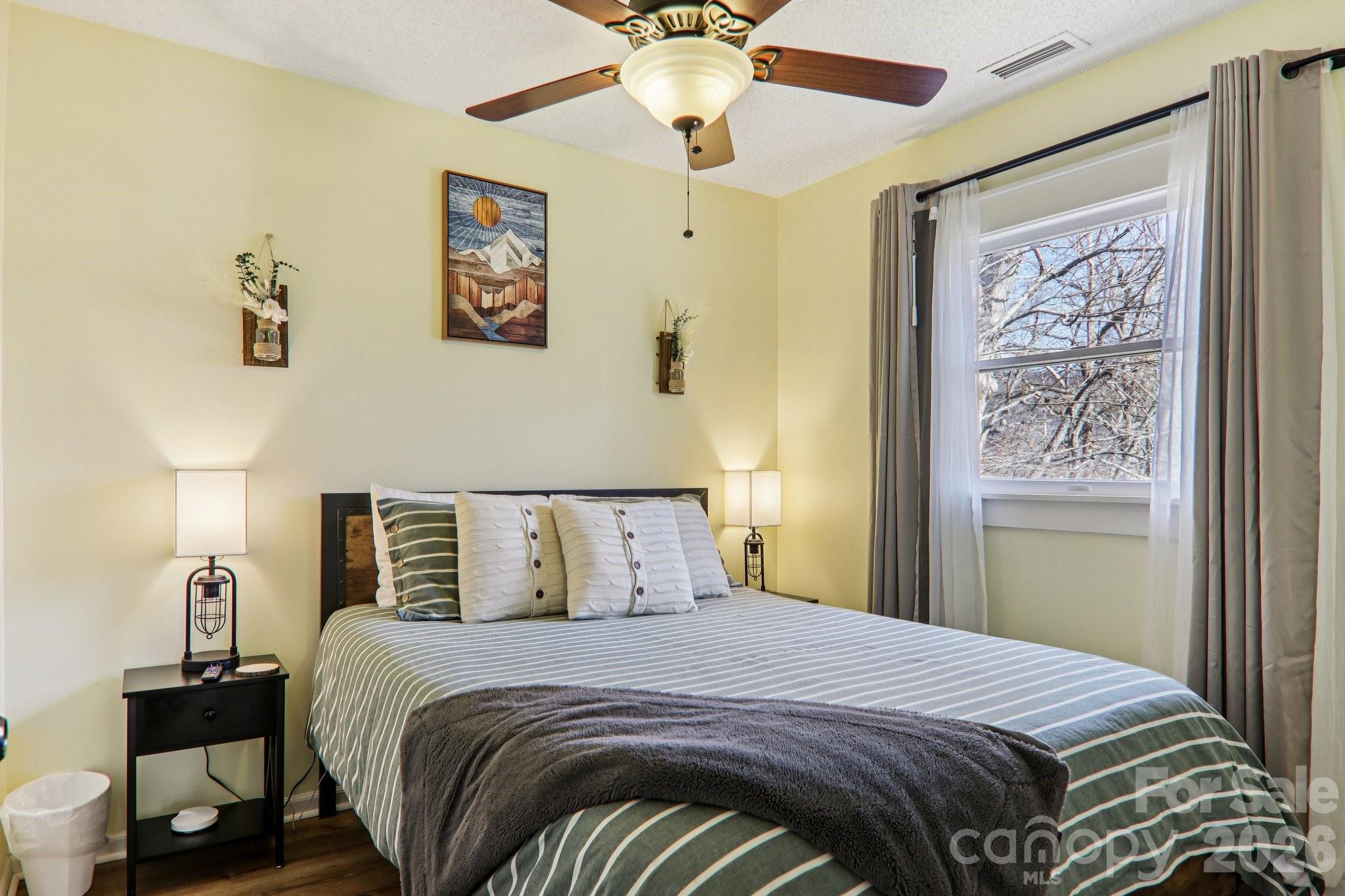 129 Riverside Villa Drive Maggie Valley, NC 28751 - Photo 24 of 43 a bedroom with a bed and a chandelier