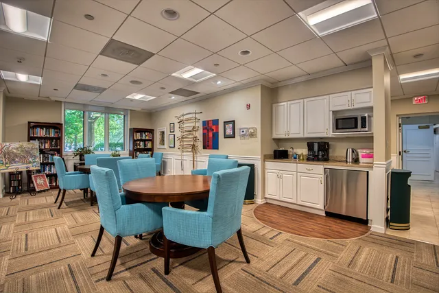 a kitchen with stainless steel appliances kitchen island granite countertop a dining table chairs refrigerator and sink