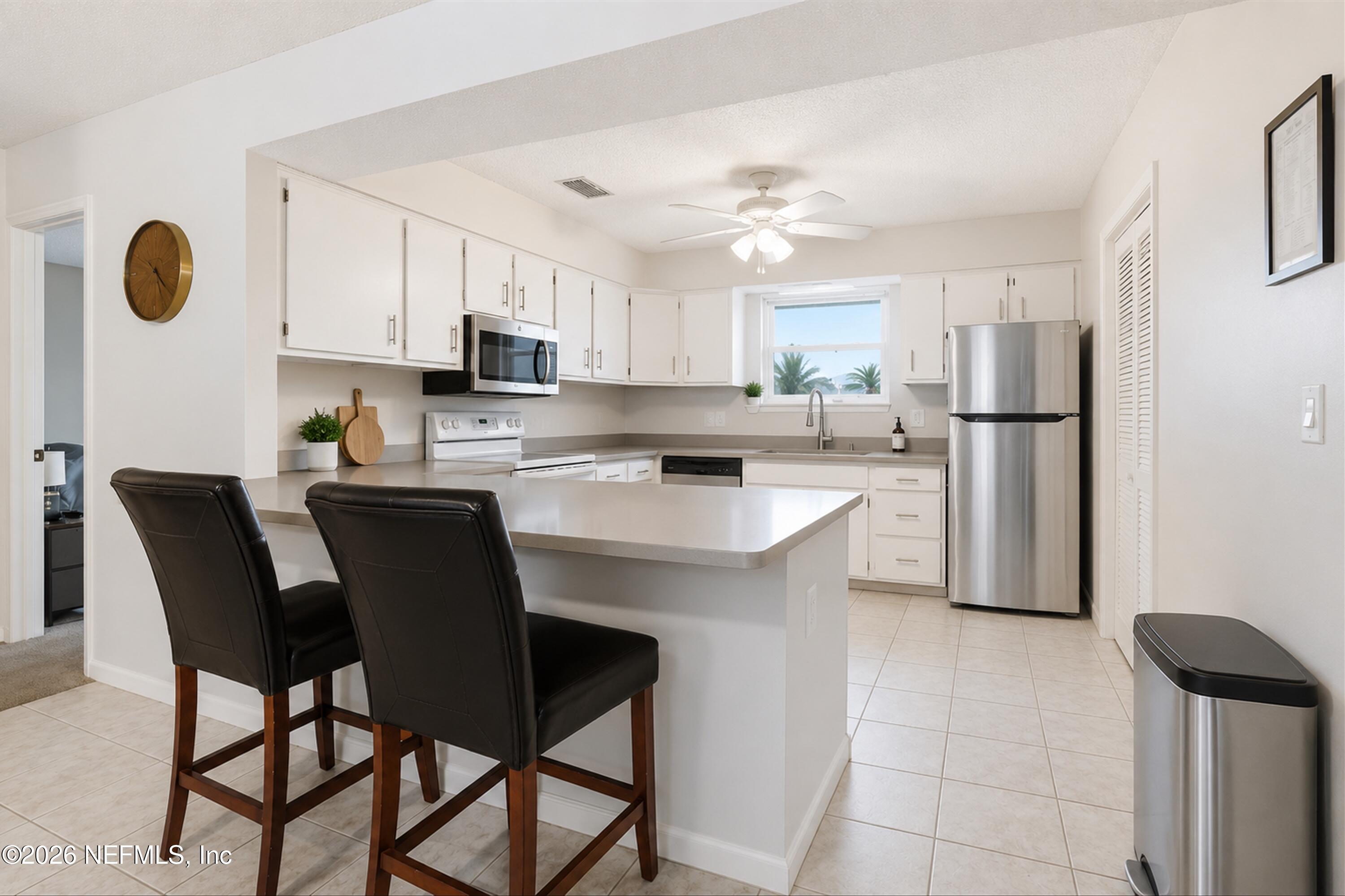 124 Hopkins Street Neptune Beach, FL 32266 - Photo 9 of 44 a kitchen with stainless steel appliances granite countertop a sink a stove a refrigerator cabinets and chairs