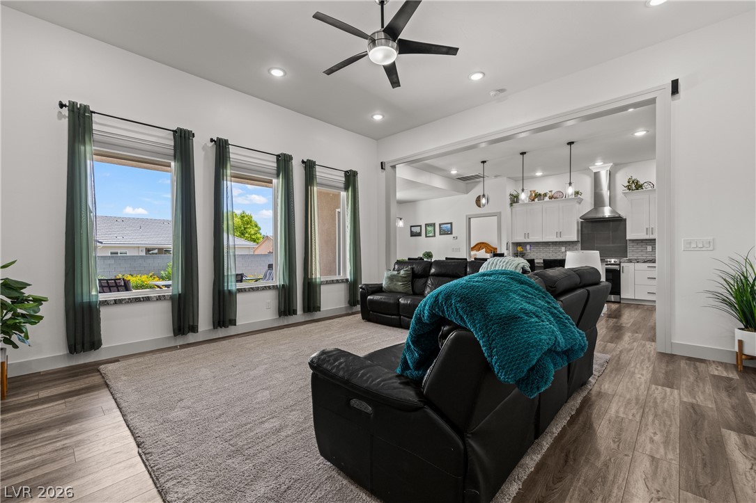 An open concept living area transitions effortlessly into a contemporary kitchen, illuminated by recessed lighting and a ceiling fan.