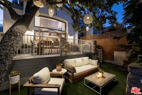 a view of a patio with couches table and chairs and potted plants
