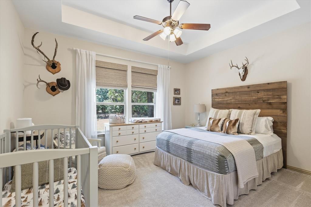 149 Overton Ridge Circle Weatherford, TX 76088 - Photo 26 of 39 Tray ceiling with a ceiling fan, light-toned walls, double windows, and a wood plank headboard