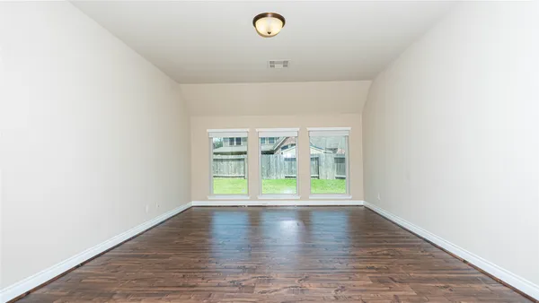 a view of a room with wooden floor water view and windows