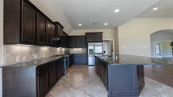 a kitchen with kitchen island granite countertop a sink a stove and a refrigerator