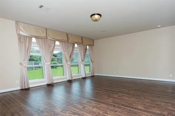 a view of an empty room with a large window and wooden floor