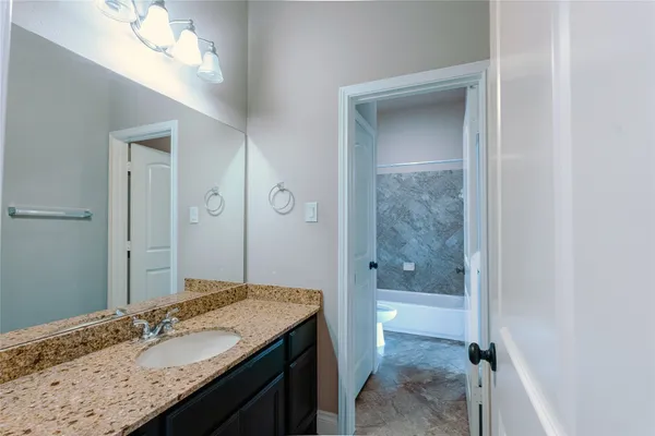 a bathroom with a granite countertop sink toilet and shower