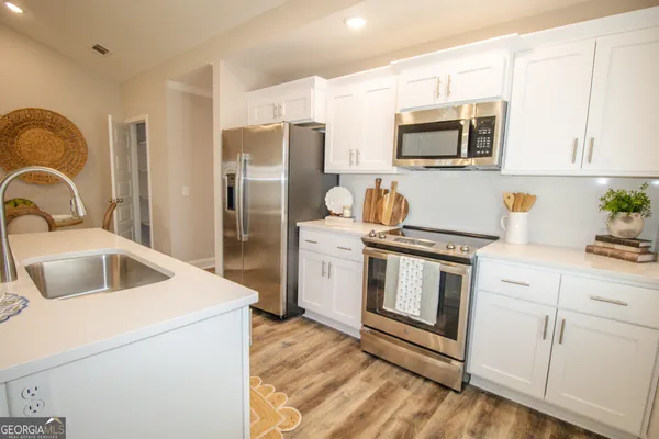 a kitchen with stainless steel appliances granite countertop a stove a sink dishwasher a refrigerator and a microwave with wooden floor