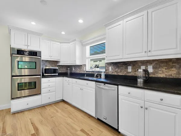 a kitchen with granite countertop white cabinets and stainless steel appliances