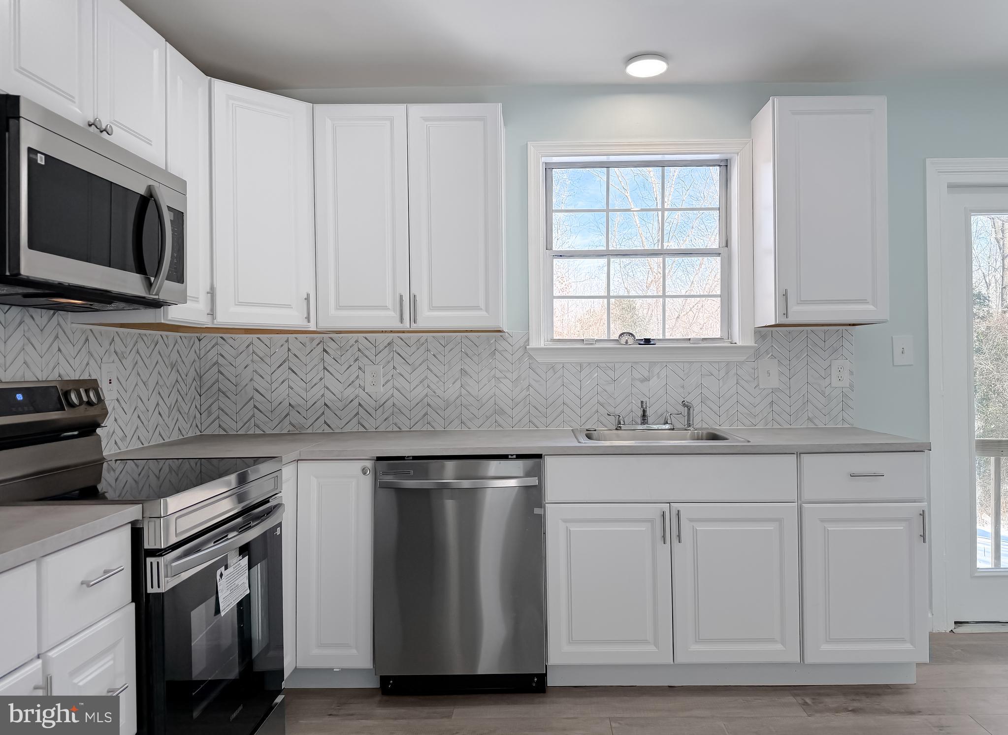 470 Sollers Wharf Road Lusby, MD 20657 - Photo 10 of 43 a kitchen with white cabinets stainless steel appliances and sink