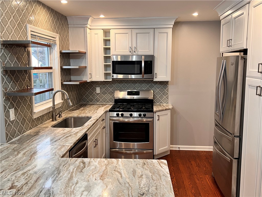 1376 Lander Road Cleveland, OH 44124 - Photo 7 of 33 Kitchen featuring light stone countertops, appliances with stainless steel finishes, dark hardwood floors, backsplash, and sink