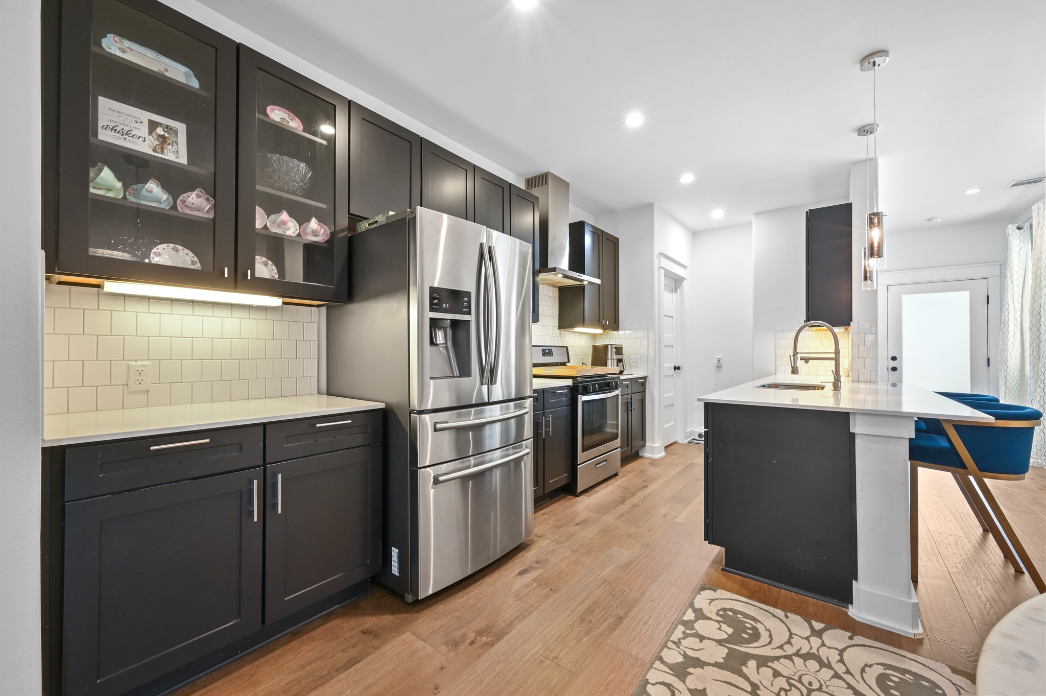 1405 Casey Street, Unit B Austin, TX 78704 - Photo 6 of 28 Kitchen with stainless steel appliances, glass fronted cabinets, light stone countertops, hanging light fixtures, and dark cabinets