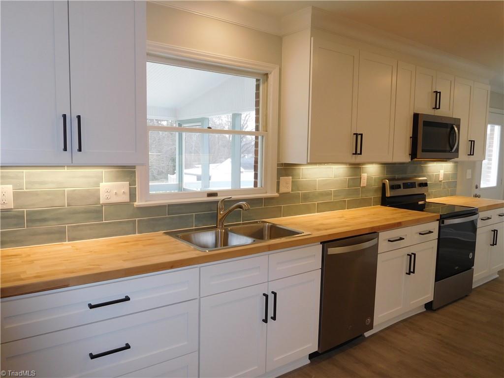 5940 Skylark Road Pfafftown, NC 27040 - Photo 10 of 42 New White Shaker cabinets w/black pulls, tile backsplash & Butcher Block Counters. Plenty of counter space and storage.