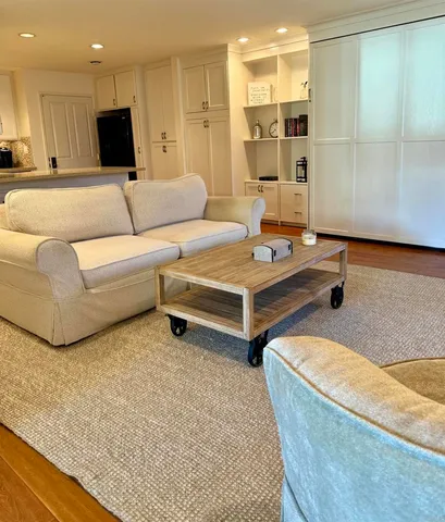 a living room with couches and kitchen view with wooden floor