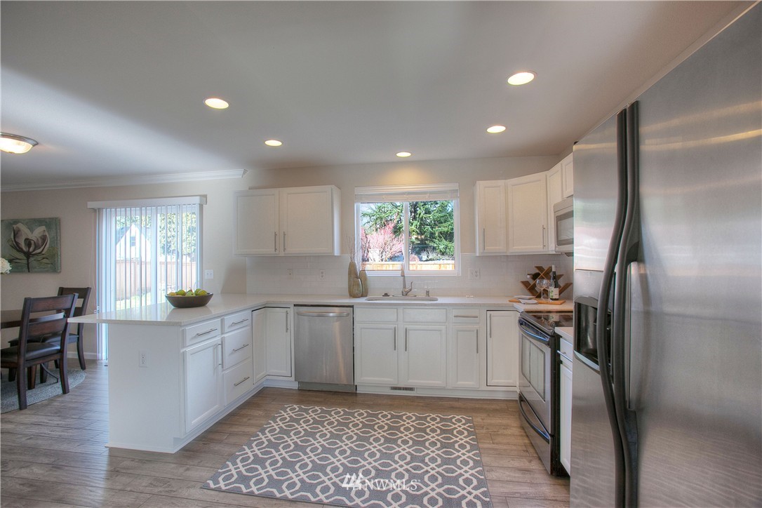 515 Harrison Street Sumner, WA 98390 - Photo 9 of 25 a kitchen with white cabinets and stainless steel appliances